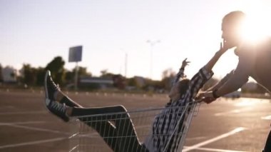 Alışveriş merkezinin boş otoparkında tramvaya binen mutlu genç çift, alışveriş sonrası iyi vakit geçiren iyi bir arkadaş, alışveriş arabasında gezen aşık bir çift. Güneş arka planda güçlü bir şekilde parlıyor