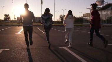 Dört arkadaş grubu eğlenceli açık havada - boş Park bölgesi tarafından yayınlanıyor mutluluk, genç erkekler ve kadınlar akşam alacakaranlık sonra freerly birlikte atlama içinde yayınlanıyor. Görünümünde nadir. Ağır çekim