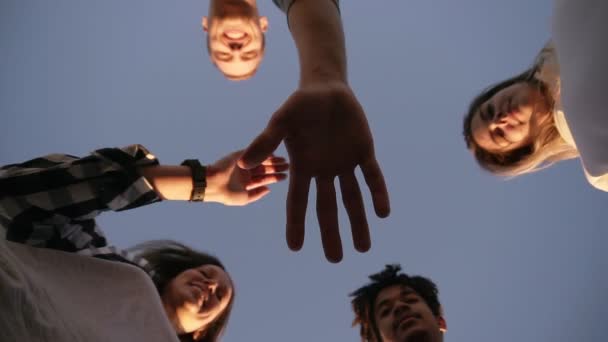 Vier jonge vrienden neer te kijken op grond die zich voordeed op zonnige dag, hand aan kant zetten. Teamwerk... Stijlvolle jeugd, gelukkig vriendschap opknoping uit elkaar en glimlachen — Stockvideo