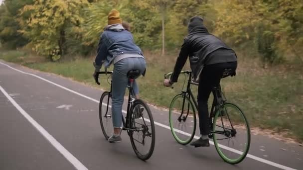 つの自転車 バイクをカップルします Earky 朝サイクリング 秋の市の公園で 男と女のバイクに乗っています アクティブな友達レジャー スローモーション まれなビュー — ストック動画