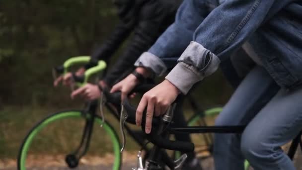 Молода пара весело катається на велосипедах в осінньому парку. Кадри веслярів руками. Люди, діяльність, концепція дозвілля. Вид збоку — стокове відео