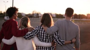 Kucaklayan ve having fun birlikte şehirde yürüyüş karışık yarış arkadaş grubu. Bunlar iki kız ve yirmili, dostluk ve yaşam tarzı kavramlar, iki erkek sonbahar giyim. Güçlü güneş