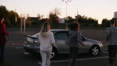 Nadir bir multirace trendy genç dört arkadaş görünümünü bölge Park Alışveriş Merkezi tarafından çalıştırılan ve gümüş renkli araba otur. İki çift birlikte vakit geçiriyor. Akşam şehir dusk