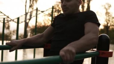 Pull ups üzerinde yatay çubuk açık havada yapıyor Genç beyaz kas erkek portresi. Atletik koşucu sabah çubuğu'nda açık havada sert eğitim. Sporcu çubuk üzerinde çalışma dışarı. Dusk