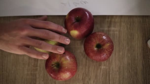 Hands of people different races takes beautiful apples from the the wooden table close up — Stock Video