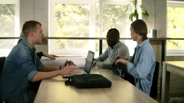 Jong gemengd ras en culturele zakenpartners of collega's hebben een vergadering samen, zitten aan de tafel open laptops en papier project. Nieuwe Start-Up project in moderne kantoor in de buurt van venster — Stockvideo