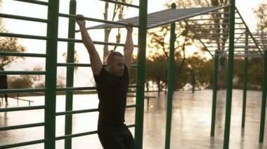 Beyaz adam egzersiz yatay çubuklar üzerinde açık havada dışarı uygun. Genç adam gönderme yapıyor eğitim abnominal muscules açık havada sabah gündoğumu sırasında ups