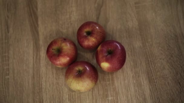 Four male and female persons different races takes beautiful red apples from the the wooden table close up — Stock Video