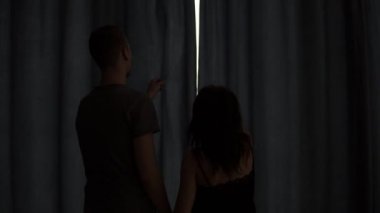 Çift pencere açık perdeleri için yürüyüş seviyorum. Sarılma ve öpüşme sabah yatak odasında beyaz erkek ve kadın dikiz. Hızlandırılmış görüntüleri