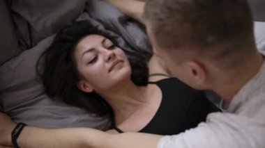 Şehvetli erkek ve kadın gri çarşaflı yatakta yalan. Ön sevişme yatakta zevk samimi genç bir çift. Üstten görünüm