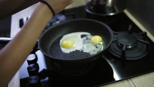 Una mujer agrieta un huevo fresco en una sartén con mantequilla caliente y chisporroteante. Desayuno tardío después de la ducha — Vídeo de stock