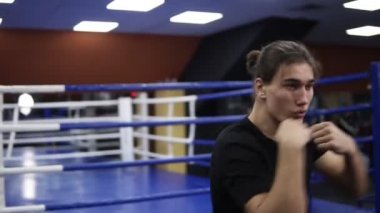 Modern bir spor salonu boks ringde üzerinde eğitim beyaz delikanlı. Gölge mücadele. Siyah T shirt ve uzun saç eğitim kick boks. Yakın çekim. Handhelded görüntüleri