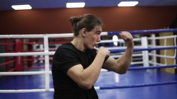 Personas, deportistas, entrenamientos, gimnasios, fitness, combate y deportes extremos. Hombre caucásico haciendo ejercicio en el gimnasio. Arte marcial, kickboxer golpeando, golpeando, luchando con la sombra — Vídeo de stock