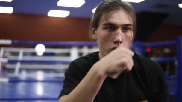 Personas, deportistas, entrenamientos, gimnasios, fitness, combate y deportes extremos. Hombre caucásico haciendo ejercicio en el gimnasio. Arte marcial, kickboxer golpeando, golpeando, luchando con la sombra. De cerca. — Vídeos de Stock