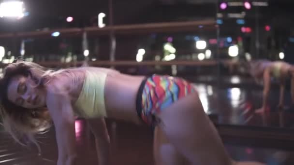 Chicas twine booty de pie. Mujer sexy y deportiva bailando en un estudio oscuro. Dulce dama en pantalones cortos mueven sus traseros en la danza, haciendo split — Vídeos de Stock