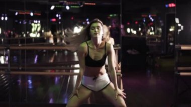 Blondy kız onun gövde ve eşek twerk stüdyoda dans hareket seksi önden görünümü. Seksi sarışın twerk dans ganimet sallayarak. Genç kız karanlıkta, ayna beyaz gömlek ve siyah stüdyo dans dans