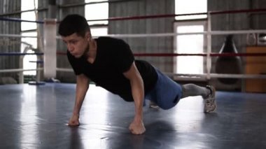 T gömlek ve onun ayak ve yumruk üzerinde duran ve boks halka içinde şınav şort atletik adam. Sert güç eğitim. Ağır çekim