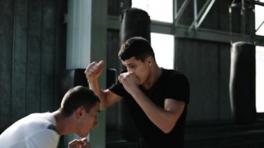 İki boksör ustaca yumruk işe. Uzakta yüz koruma darbeler gelen utangaç. Eski stil gy birlikte eğitim boks. Boks torbaları üzerinde arka plan. Ağır çekim