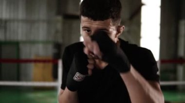 Bandaj boks ve spor salonunda kamera ciddi seyir siyah Delme koyu saçlı genç adam. Egzersiz boksör yorgun kapatın. Gücü. güçlü beden. Ağır çekim