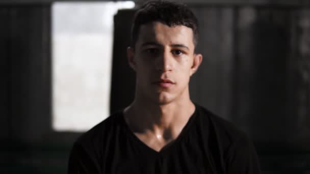 Portrait of a dark haired caucasian male boxer standing in an old fashioned boxing gym near the sand bag. Wearing casual clothes and black gloves. Sweaty and exhausted after training. "Move away — Stock Video