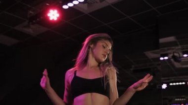 Twerk studio dans blondy, kıçını hareket seksi kız. Seksi sarışın twerk dans ganimet sallayarak. Beyaz gömlek ve siyah sütyen stüdyoda dans dans karanlık, genç bir kız. Ağır çekim. Düşük açılı görünüş