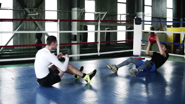 İki kaslı adam trenler birlikte karın için şınav ve ağır sportif topu atma işlemi sırasında spor salonunda. Kavramı: egzersiz, boks egzersiz, güç, zor iş — Stok video