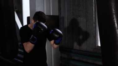 Erkek boxer eğitim. Güçlü, sert sayısı boks çanta üzerinde yapıyor. Beyaz genç adam egzersiz jimnastik salonu, çalışkan, motivasyon. Yan görünüm