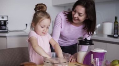 Mutlu genç kız annesiyle hamur yapma. Anne ve kızı mutfakta pişirme. Kız elleriyle hamur karıştırmaya çalışıyor