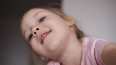 Oynak bir küçük sarışın sevimli kız yüzünü kapat. Gözleri yanıp sönen ve gülümseyen kız. Portre vurdu