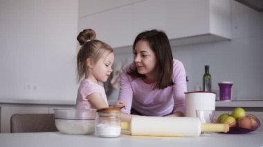 Anne ve kızı biraz un hamur koyarak. Anne kızı bir hamur yoğurmak için öğretir. Modern, parlak mutfak