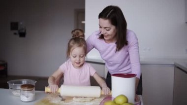 Sevimli küçük kızını birlikte mutfakta yemek yaparken bir oklava ile hamur yayıyoruz öğretim güzel genç sevgi dolu bir anne. Yemek ve eğlence