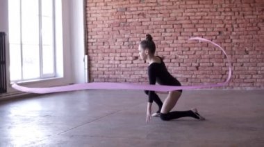 Minik kız Stuido yalnız dans egzersiz. Dans, pembe kurdele ile iplik. Ağır çekim görüntüleri. Tuğla duvar arka planda