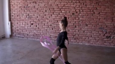 Genç kız dansçı trenler dans salonunda. Küçük kız dans ve farklı bale hareketleri yapıyor. Hobi ve sağlıklı bir yaşam tarzı. Çocuk uzmanları. Kızlar için ritmik jimnastik