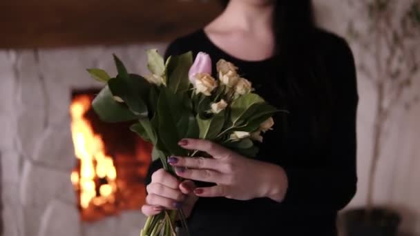 Unrecognizable female florist holding a half made bouquet and adding flowers to composition. Designing, floral workshop, leisure. Blurred picture of fireplace on the background — Stock Video