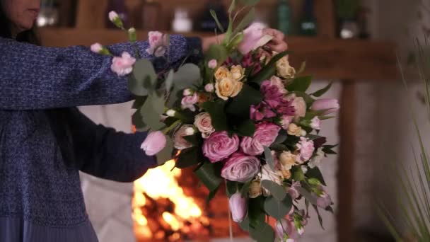 De bloemist meisje houdt in haar hand een afgewerkte bouquet van rozen en planten op lange stengels, strak koppelverkoop het boeket met lint. Close-up beelden — Stockvideo