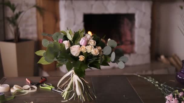 Schöner Strauß pastellfarbener Blumen steht nach dem Blütenmeisterkurs an den Stängeln auf einem grauen Tisch. Blumen Dekoration Design-Konzept. Kamin im Hintergrund — Stockvideo