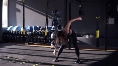 Siyah bir sportsuit güzel genç ince kadın atlet yamaçları - eğitim önce ısınmak yapar. Spor salonunda uzanan bir kızın Önden Görünüm
