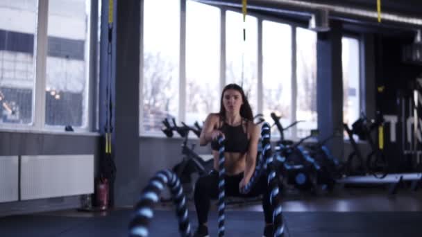 Filmagem frontal de determinada mulher de meia-idade lutando contra cordas no ginásio durante o treino de cross-training. Movimento lento — Vídeo de Stock