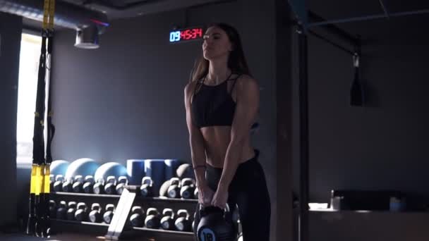 Mulher fisiculturista em sportswear fazendo crossfit treino com 10 quilos de sino de chaleira. Esporte, equipamentos de ginástica em segundo plano Confiante ansioso jovem atleta com corpo muscular exercitando crossfit — Vídeo de Stock