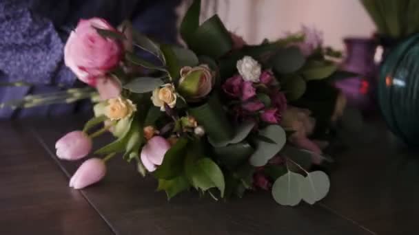 Volwassen bloemist meester regelen het grote assortiment bloemen en planten op de teller voor de toekomstige samenstelling. Workshop, ontwerpen van bloemen, handwerk concept. Open haard op de achtergrond — Stockvideo