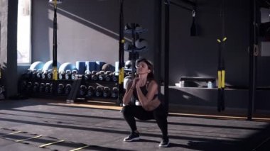 Profesyonel sporcumuz siyah eşofman kas ve bacaklar için butt egzersiz yaparak tam uzunlukta. Çekici kız modern bir spor salonu derin sit up pratik