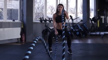 Savaş halatlar ile spor salonunda eğitim kadın. Güçlü çekici beyaz kadın ile ipleri ağır çekimde spor salonunda egzersiz savaş. Önden Görünüm