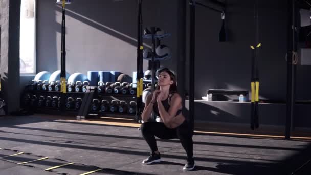 Comprimento total de esportista profissional em sportwear preto fazendo exercício para músculos e pernas bunda. Menina atraente está praticando profundamente sit ups no ginásio moderno — Vídeo de Stock