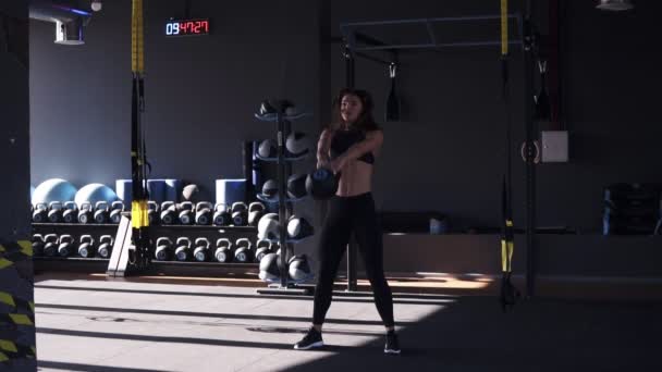 Comprimento total de menina fitness em sportswear fazendo crossfit treino com sino de chaleira de 10 quilos. Levantando alto sob a cabeça grande, kettlebell preto com as mãos estendidas. Esporte, equipamentos de ginástica no — Vídeo de Stock