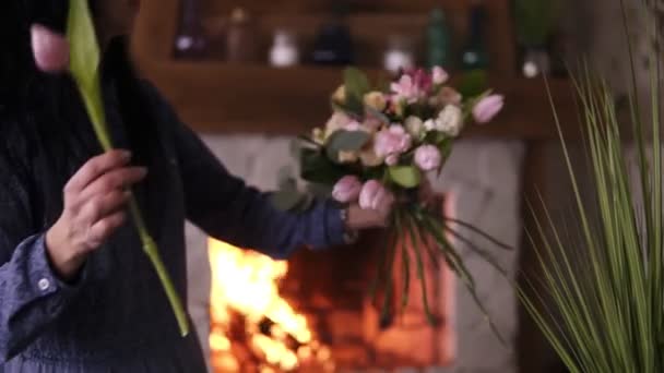 Bloemist op het werk: professionele bloemist aanbrengen mode modern boeket van verschillende bloemen en planten op thuisstudio door toe te voegen roze tulpen samenstelling. Close-up — Stockvideo