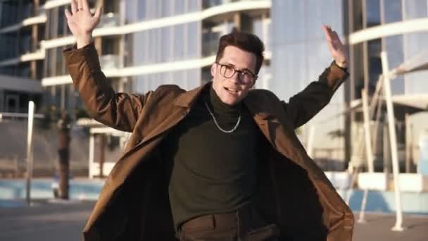 Atractivo morena joven hombre con gafas de estilo y collar de oro está realizando danza moderna estilo libre al aire libre en brillante, día soleado. Expresión. Vista frontal — Vídeo de stock