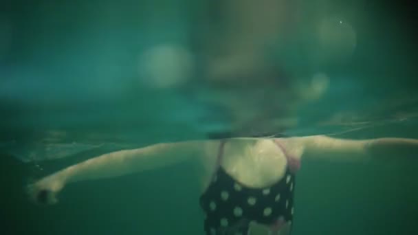 Menina sorridente sem óculos de natação nadando debaixo d 'água na piscina. Menina adolescente mergulhando debaixo d 'água. Filmagem acima e abaixo da água — Vídeo de Stock