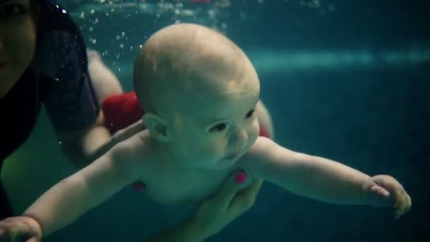Boldog család-anya a baba fia merülés víz alatti szórakoztató medence. Egészséges életmód, aktív szülő, úszás oktatás a beltéri úszómedence gyermekmedencében — Stock videók