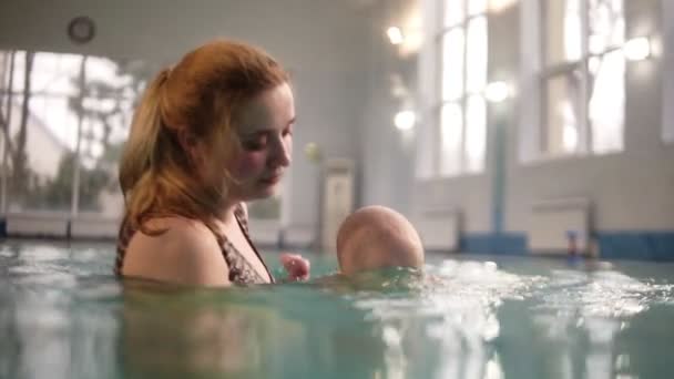 Jovem mãe ensina seu menino bonito para mergulhar na piscina. A criança está encantada. O desenvolvimento dos filhos, a paternidade. Piscina interior. Movimento lento — Vídeo de Stock