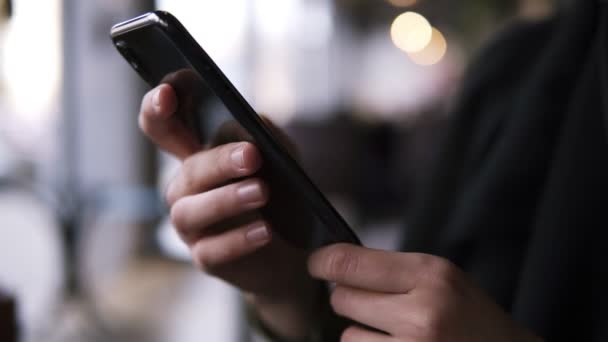 Close up of females hands holding smartphone with fingers on a touchscreen. Woman browsing internet on a mobile phone. Slow motion. Blurred background — Stock Video